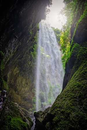 Wulong, China - August 2019 : Crowd of tourists walking on a narrow path under the Giant Waterfall in a valley gorge in the Longshuixia Fissure National park, Wulong country, Chongqingのeditorial素材