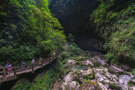 Wulong, China - August 2019 : Tourists walking on a wooden artificial walkway path going along the stream river flowing through the gorge and the landscape of Wulong National Parkのeditorial素材