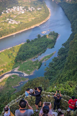 Yangshuo, China - August 2019 : Tourists admiring stunning panoramic view of the beautiful green, lush and dense karst mountain landscape in Yangshuo as seen from Xianggong Hill viewpoint, Guangxi Provinceのeditorial素材