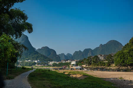 Yangshuo, China -  August 2019 : Empty walking path along the shore of the Li river  with small tourist and fishermen boats on the riverbank, the ferry crossing point in town, Guangxi Provinceのeditorial素材
