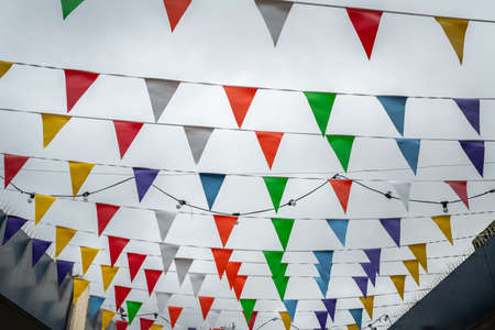 Colorful flags fluttering in the wind above the street market in the Catford Centre in Lewisham,...
