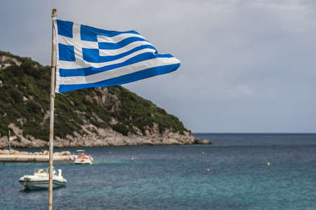 Greek flag fluttering in the wind in Agios Nikolaos port on Zakynthos Island, Greeceの写真素材