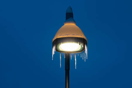 Street lamp covered in snow and icicle during blizzard and snowfall, Tromso, Norway