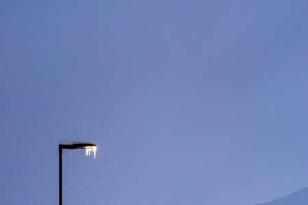 Street lamp covered in snow and icicle during blizzard and snowfall, Tromso, Norway