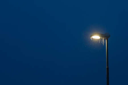 Street lamp covered in snow and icicle during blizzard and snowfall, Tromso, Norway