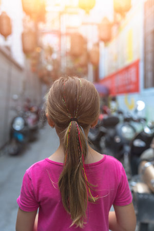 Young Caucasian girl with braided hair and ponytail standing in narrow street passage in Feng Huang Old Town, Hunan Province, Chinaの写真素材