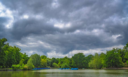 View of a small boating lake pond with a row of paddle boats parked, Crystal Palace Park, London,...