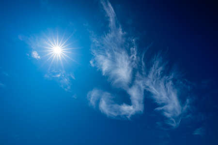 Horizontal picture of clouds in the sky on a clear warm summer afternoon with sunshineの写真素材