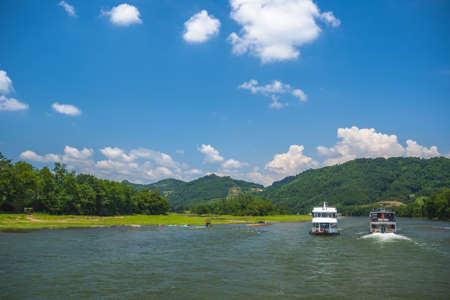 Sightseeing boats carrying tourists sailing among high vertical cliffs of karst mountains on the magnificent Li river flowing between Guilin and Yangshuo towns, Chinaのeditorial素材