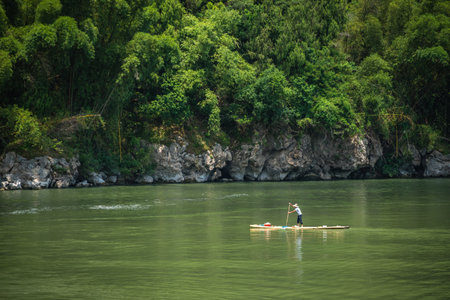 Yangshuo, China - August 2019 : Old fisherman paddling on a small narrow wooden boat among stunning karst mountain scenery on the magnificent Li riverのeditorial素材