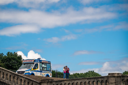 London, UK - June 2020 : Man and woman eating ice creams bought from Ice cream Van parked on top of walking stairs in Crystal Palace Park in summerのeditorial素材