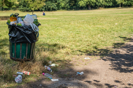 London, UK - July 2020 : Overflowing large rubbish and litter garbage and waste bin  in a nature Parkのeditorial素材