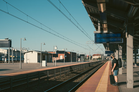 Bydgoszcz, Poland - August 2020 : Middle aged male man wearing protective face mask, pulling a wheeled luggage trolley standing alone on an empty platform awaiting arrival of a scheduled train, traveling in the time of covid19 pandemicのeditorial素材