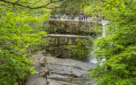 Ystradfellte Neath, Wales - May 2021 : People and tourists admiring rapid water of a  tall waterfall, UKのeditorial素材