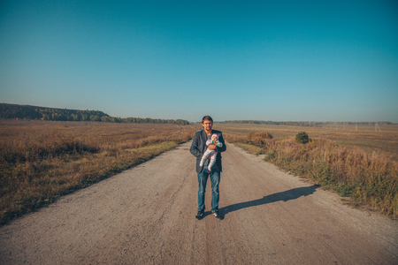 A man with a child in his arms on the road in the middle of a wastelandの写真素材