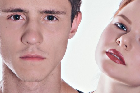 Cropped image of beautiful couple looking at each other and smiling while standing straight on gray backgroundの写真素材
