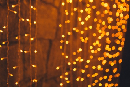 many blurred small electric bulbs on a wall. Yellow blurred lights. Wall of Christmas lights
