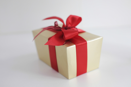 Beige square gift box with red bow on white backgroundの写真素材