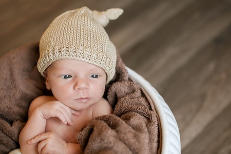 A little child in a beige cap lies in the basketの写真素材