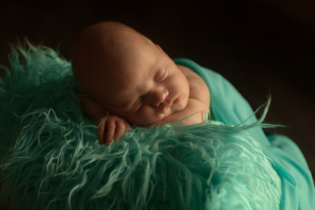 A little child in a greeen diaper lies on a black backgroundの写真素材