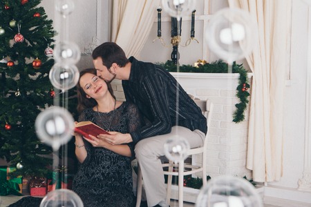 guy and girl reading a book at Christmas by the fireplaceの写真素材