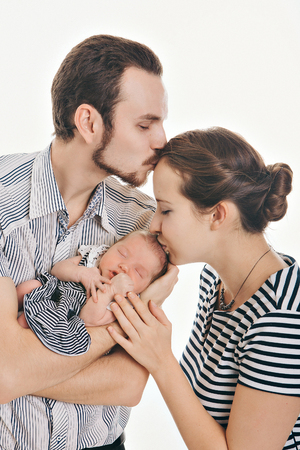 newborn baby lying on the hands of parents on a white background.の写真素材