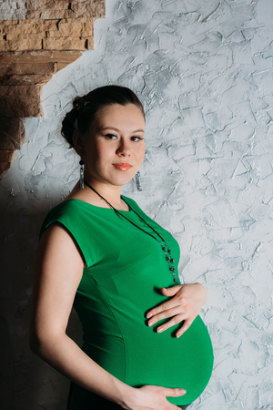 Portrait of pregnant woman in long dress on white backgroundの写真素材