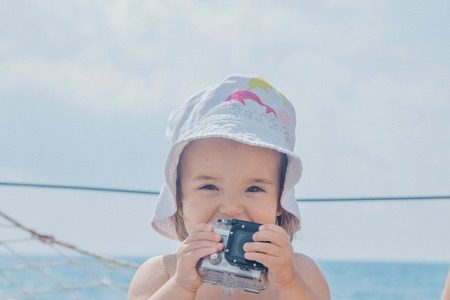 Portrait of a little girl with camera on a background of sea