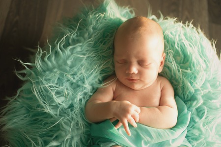A little child in a green diaper lies on a green backgroundの写真素材