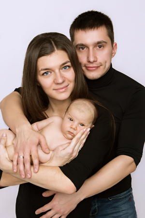 newborn baby lying on the hands of parents on a white background.の写真素材