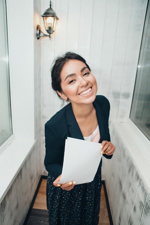 girl in a business suit Asian appearance on a white background in the office working with documentsの写真素材