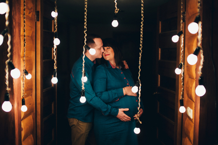 Man hugs his pregnant woman on a lamps backgroundの写真素材