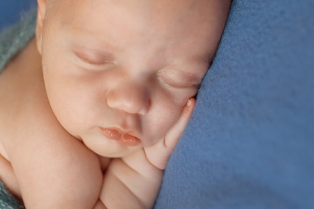 newborn baby lying on a blue background. Imitation of a baby in the womb. beautiful little child...