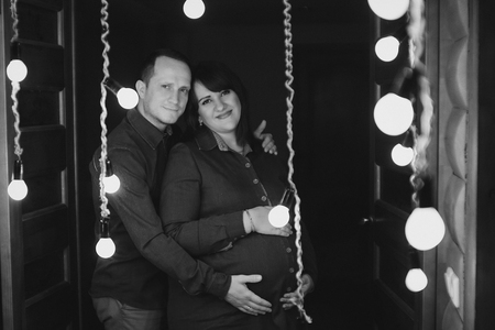 Man hugs his pregnant woman on a lamps backgroundの写真素材