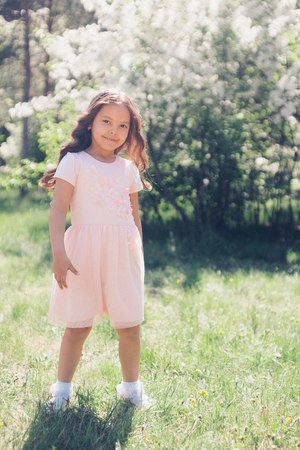 Portrait of a girl on a background of green foliage. children's fashionの写真素材