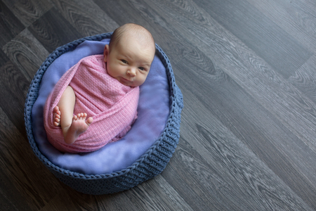 A little child in a pink cap lies on a blue and grey backgroundの写真素材