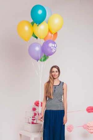 Studio portrait of an attractive girl waiting for her birthday. Face and balloonsの写真素材