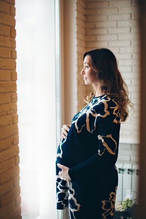 pregnant woman looking out the windowの写真素材