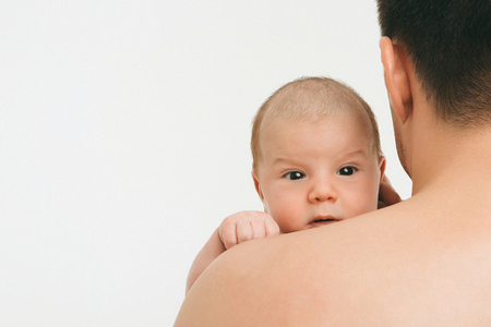 baby peeking out from behind dad's shoulder on white background. Man and childの写真素材