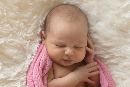 A little child in a pink diaper lies on a beige backgroundの写真素材