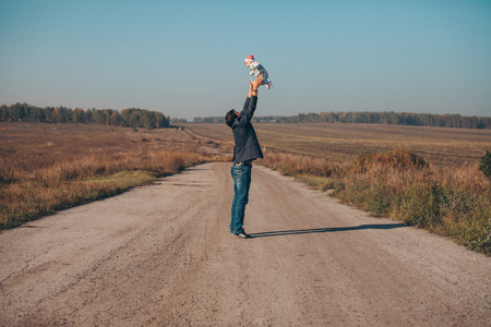 A man with a child in his arms on the road in the middle of a wastelandの写真素材