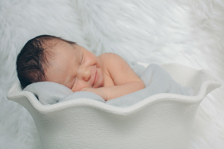 A little child lies in the white basketの写真素材