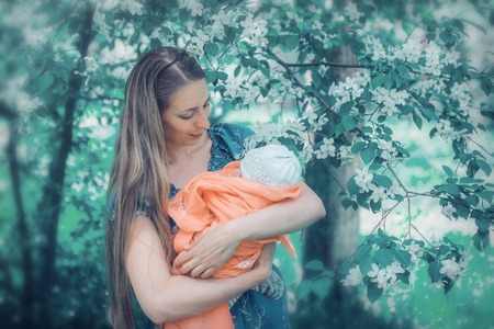 Portrait of a girl with baby on a background of green foliageの写真素材