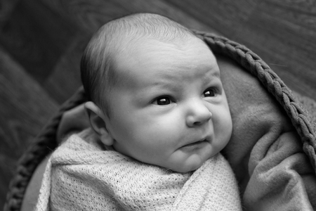 Portrait a little child in a cap lies on a basket. Face of newbornの写真素材