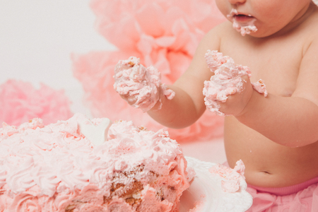 little baby girl eating pimk cake isolated white backgroundの写真素材