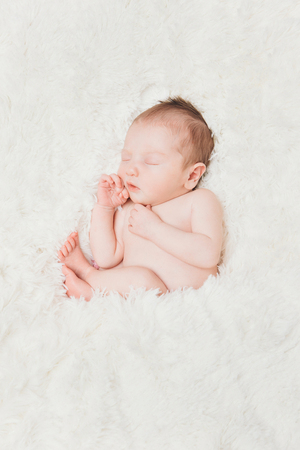 newborn baby lying on a white background. Imitation of a baby in the womb. beautiful little girl sleeping lying on her back.の写真素材