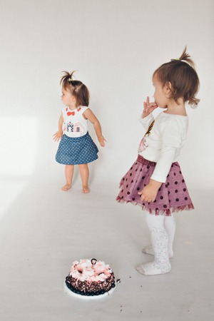 Two little baby girl eating cake isolated white backgroundの写真素材