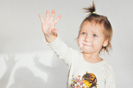 the little girl got her hand dirty in the cake. Isolated shot on white background. dirty hand of a child in the foodの写真素材