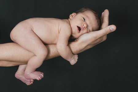 baby on the hands of parents on a black background.の写真素材