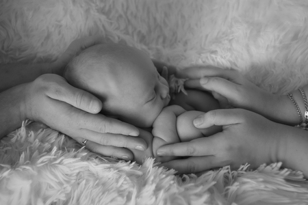 newborn baby lying on a white and black background. Imitation of a baby in the womb. beautiful little child sleeping lying on her tummy. Portrait of newbornの写真素材